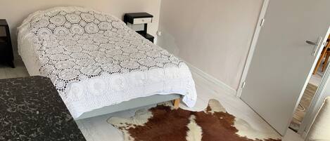 Una habitación con una cama, una mesita de noche pequeña, un tapete de cuero de vaca y una encimera de mármol.