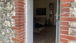 A doorway leading into a room with a wooden floor, a sofa, and a wall clock.