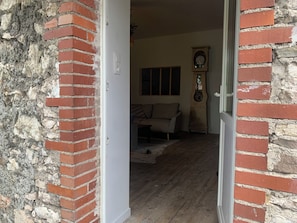 Una puerta que da a un cuarto con piso de madera, un sofá y un reloj de pared.
