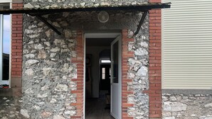 A building entrance with a stone facade, a door, and a small step leading inside.