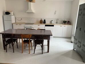 A modern kitchen with white cabinets, a wooden dining table, and a built-in oven. - Pleasant 3-bedroom house with garden near Albi (Carmaux)