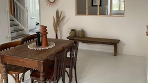 A dining area with a wooden table, chairs, a hanging light fixture, a mirror, and a bench.