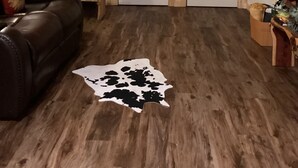 Un interior de madera con un sofá de cuero, un tapiz de cuero de vaca y un cuarto de lavado con dos puertas blancas.