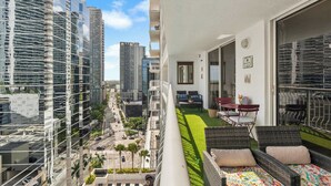 A balcony with a view of a cityscape, a small lawn area, and outdoor furniture. - Plush Brickell 1BR | Free Parking | Resort Pool (Brickell)