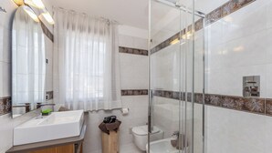 A modern bathroom with a large mirror, a sink, a toilet, and a shower area. - Apt "Homewood": rustic design with park and biolago (Pinzolo)