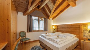 A bedroom with a wooden ceiling, a bed, a chair, a window with curtains, and a nightstand. - Apt "Homewood": rustic design with park and biolago (Pinzolo)