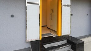 A hotel entrance with a glass door, a metal handle, and a yellow frame. - Deluxe Zafe Commercial (Chengalpattu)