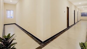 A spacious corridor with a marble floor, a window with bars, and a door at the end. - Deluxe Zafe Commercial (Chengalpattu)