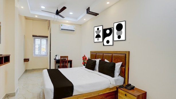 A bedroom with a wooden bed, bedside table, and a ceiling fan. - Deluxe Zafe Commercial (Chengalpattu)