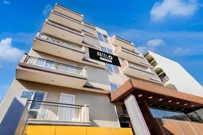 Monikerroksinen hotellirakennus, jossa on parvekkeita, ja sen yläpuolella on kyltti, jossa lukee ”HOTEL”, ja taivaalla on kirkas, sininen taivas.