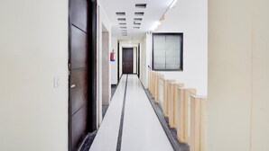 A hallway with a tiled floor, a fire extinguisher, a door, and a window. - Townhouse Sector 51 Noida (Noida)
