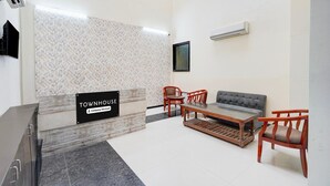 A reception area with a sign reading 'TOWNHOUSE Company Serviced,' a sofa, chairs, a table, and a tiled floor. - Townhouse Sector 51 Noida (Noida)