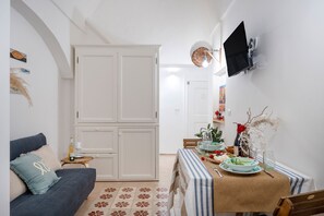 A living room with a sofa, a dining table set for two, a TV mounted on the wall, and a wardrobe. - Dimora Sardaro - Suite with Pool by BarbarHouse (Monopoli)