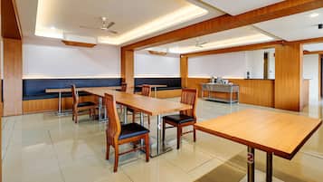 A spacious dining area with wooden tables and chairs, a counter, and ceiling fans.