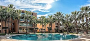 Uma piscina rodeada por palmeiras e edifícios modernos.