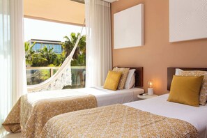 A hotel room with two beds, a hammock, a view of palm trees, and a large window. - Herdade dos Salgados (Albufeira)