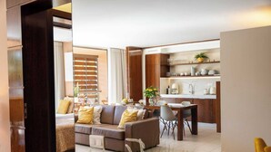 A modern living room with a sofa, dining table, and kitchen area. - Herdade dos Salgados (Albufeira)