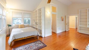 A bedroom with a bed, a ceiling fan, built-in shelving, and a large window. - Calma Azul ~ A Retreat in the Heart of C-Ville (Charlottesville)