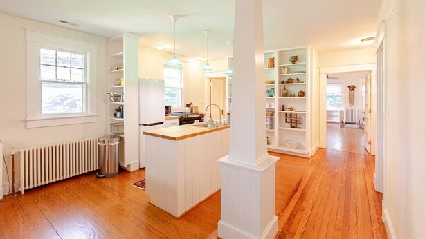A spacious kitchen with a central island, white cabinetry, and a view into the dining area. - Calma Azul ~ A Retreat in the Heart of C-Ville (Charlottesville)