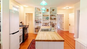 A kitchen with a central island, white cabinetry, and a hanging light fixture. - Calma Azul ~ A Retreat in the Heart of C-Ville (Charlottesville)