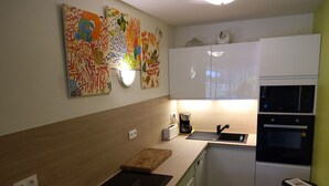 Eine moderne Küche mit weißen Schränken, einer schwarzen Arbeitsplatte, einer Kaffeemaschine und einer Mikrowelle.