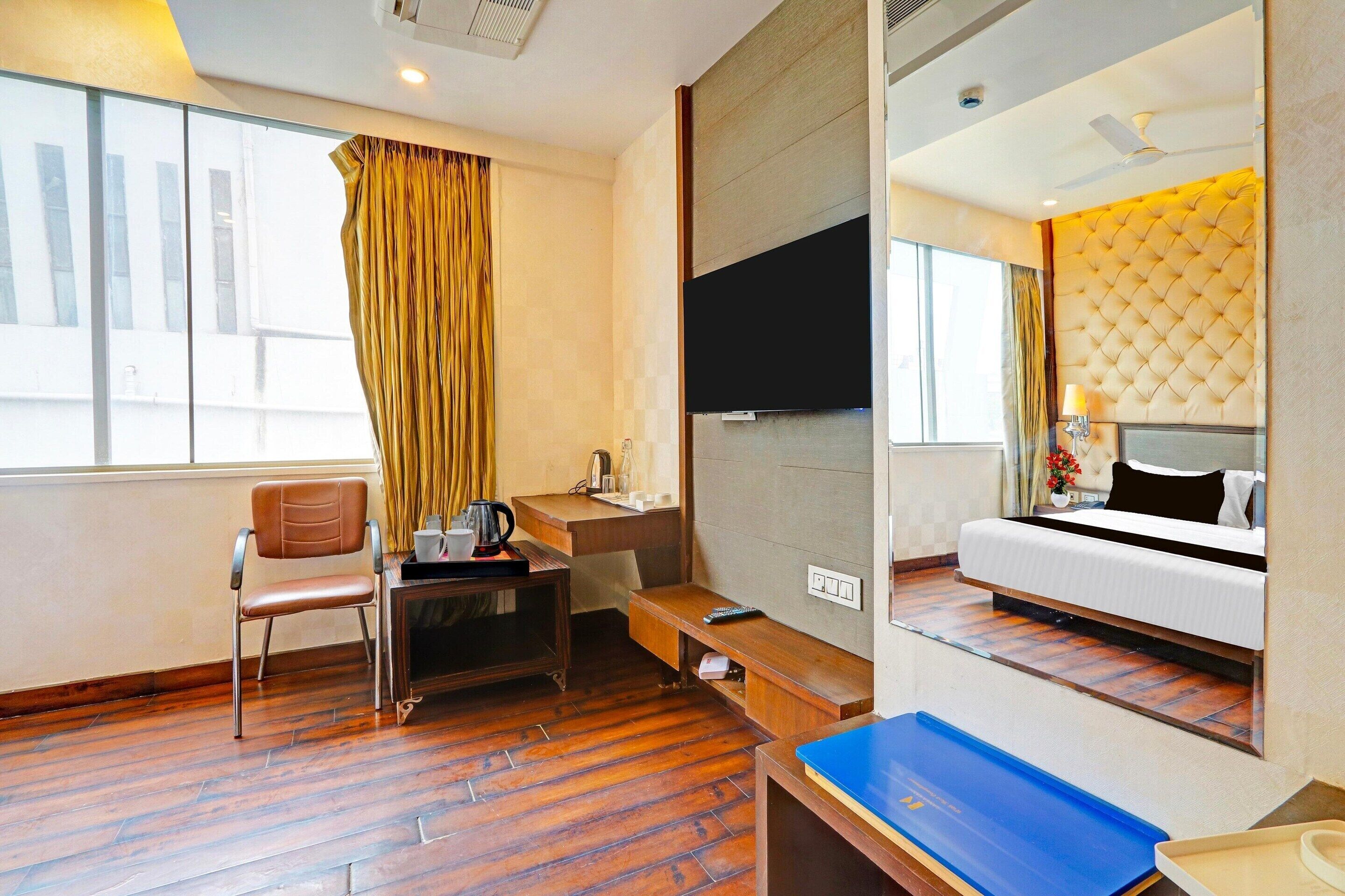 A hotel room with a bed, a desk, a chair, a TV, and a large window.