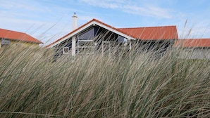 Een huis met een rood dak, omgeven door hoog gras.