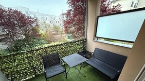 Un balcon avec un canapé, une petite table et une chaise.