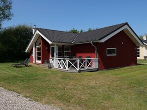 Ein rotes Gebäude mit überdachter Terrasse und einer kleinen Holzterrasse.