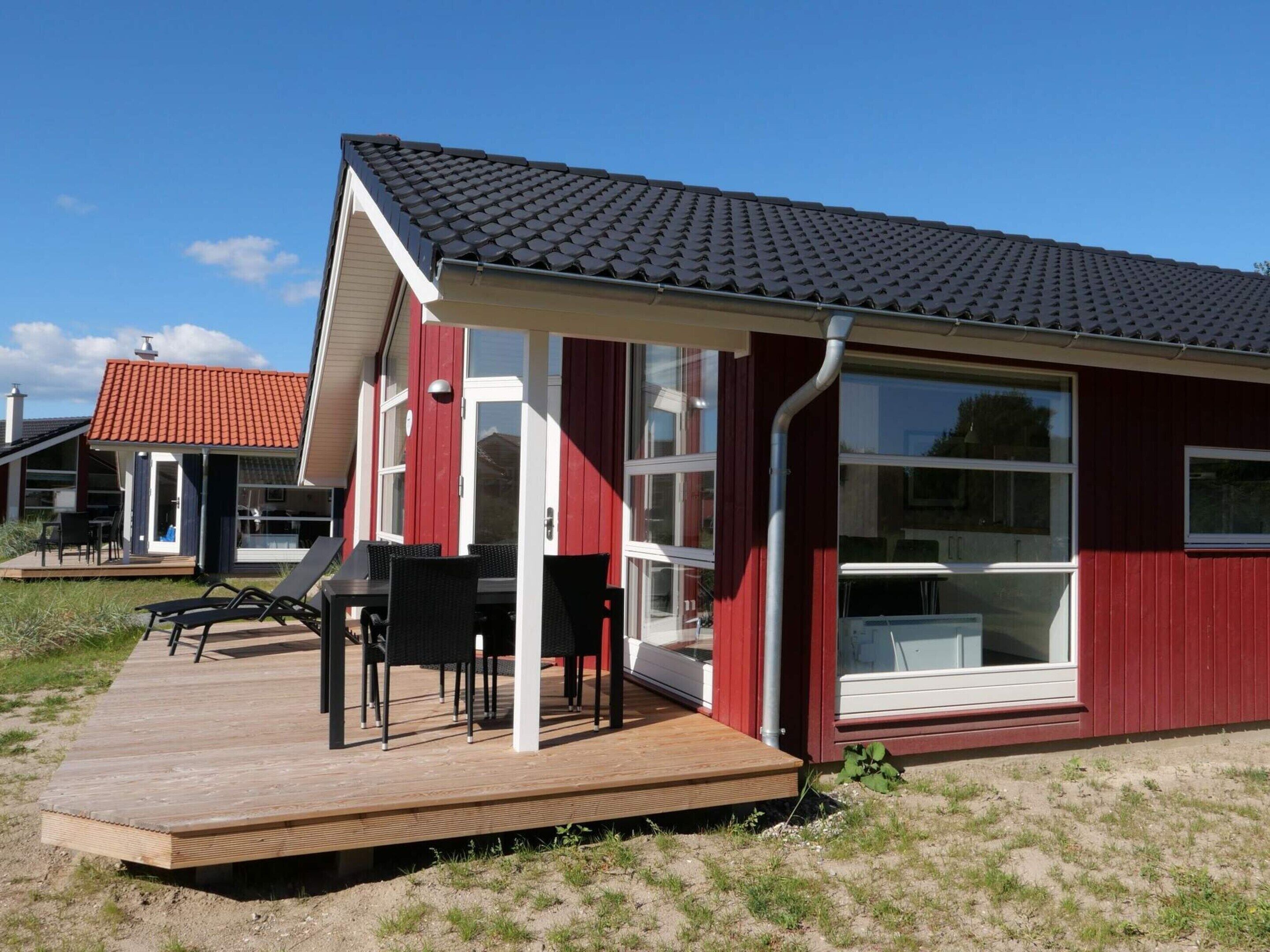 A red building with a covered patio, large windows, and a wooden deck.