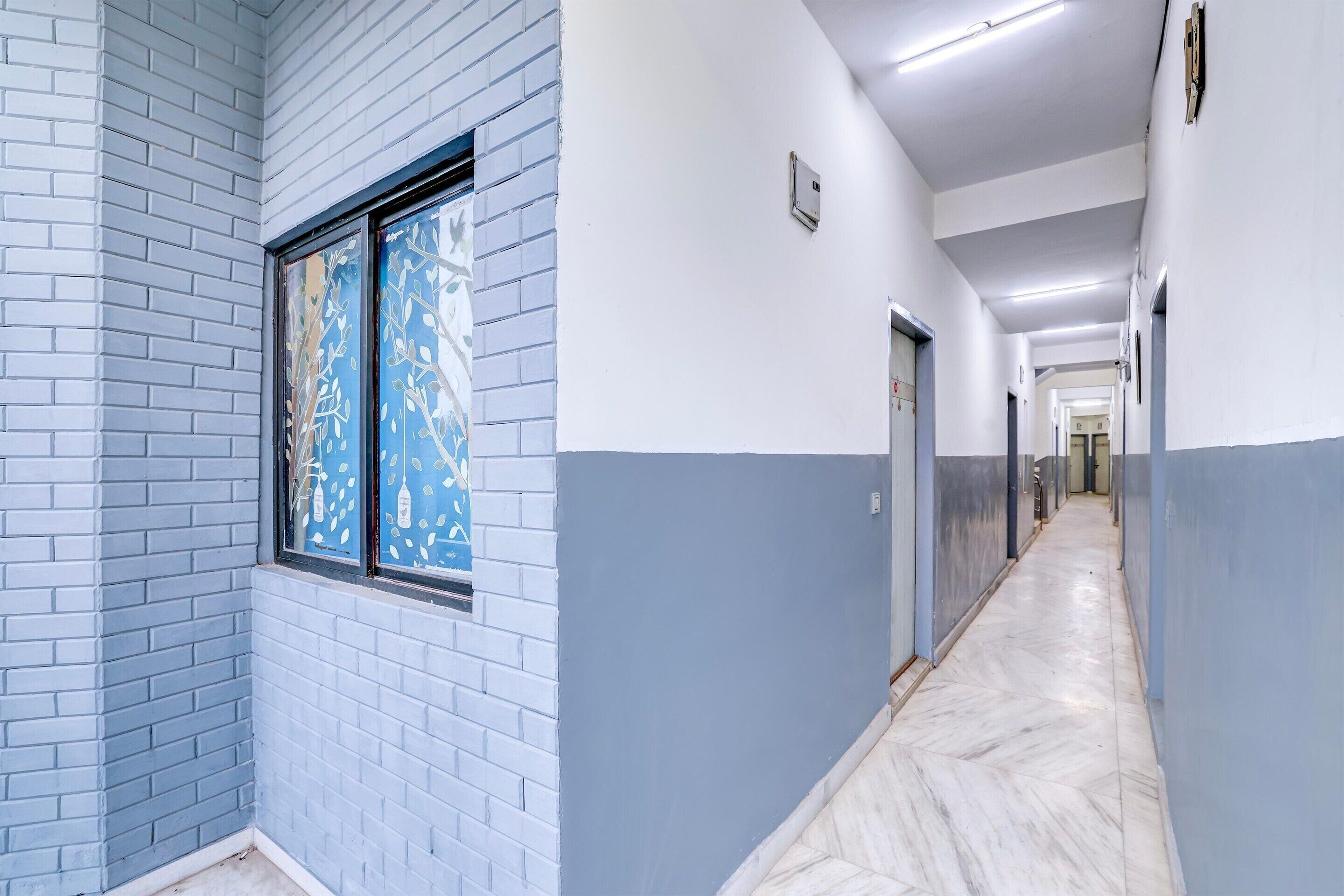 A hallway with a blue and white color scheme, a window with a decorative pattern, and a marble floor.