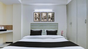 Ein Hotelzimmer mit Bett, Nachttisch, Kleiderschrank und drei gerahmten Bildern an der Wand.