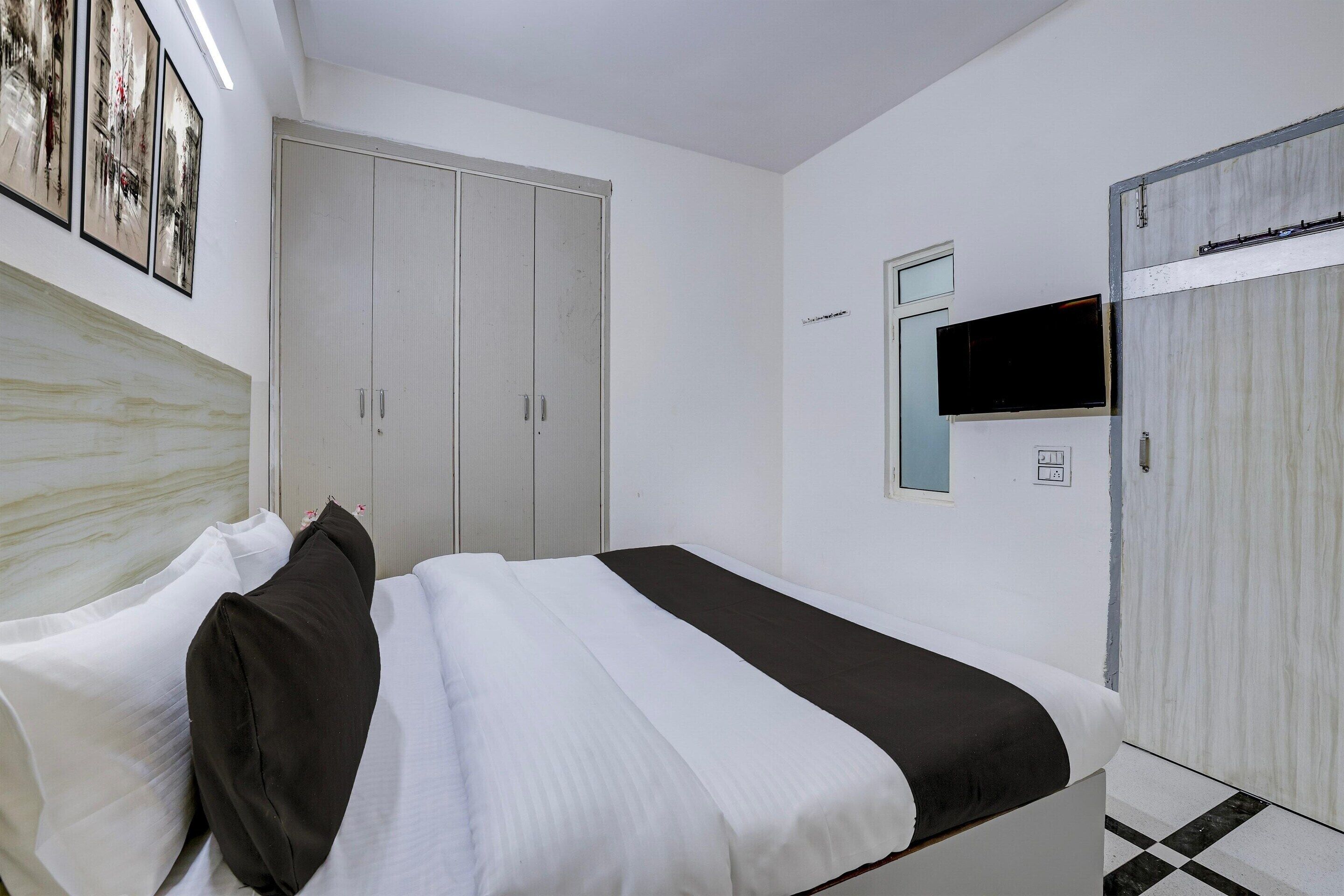 A bedroom with a bed, a wardrobe, a television, and a door.