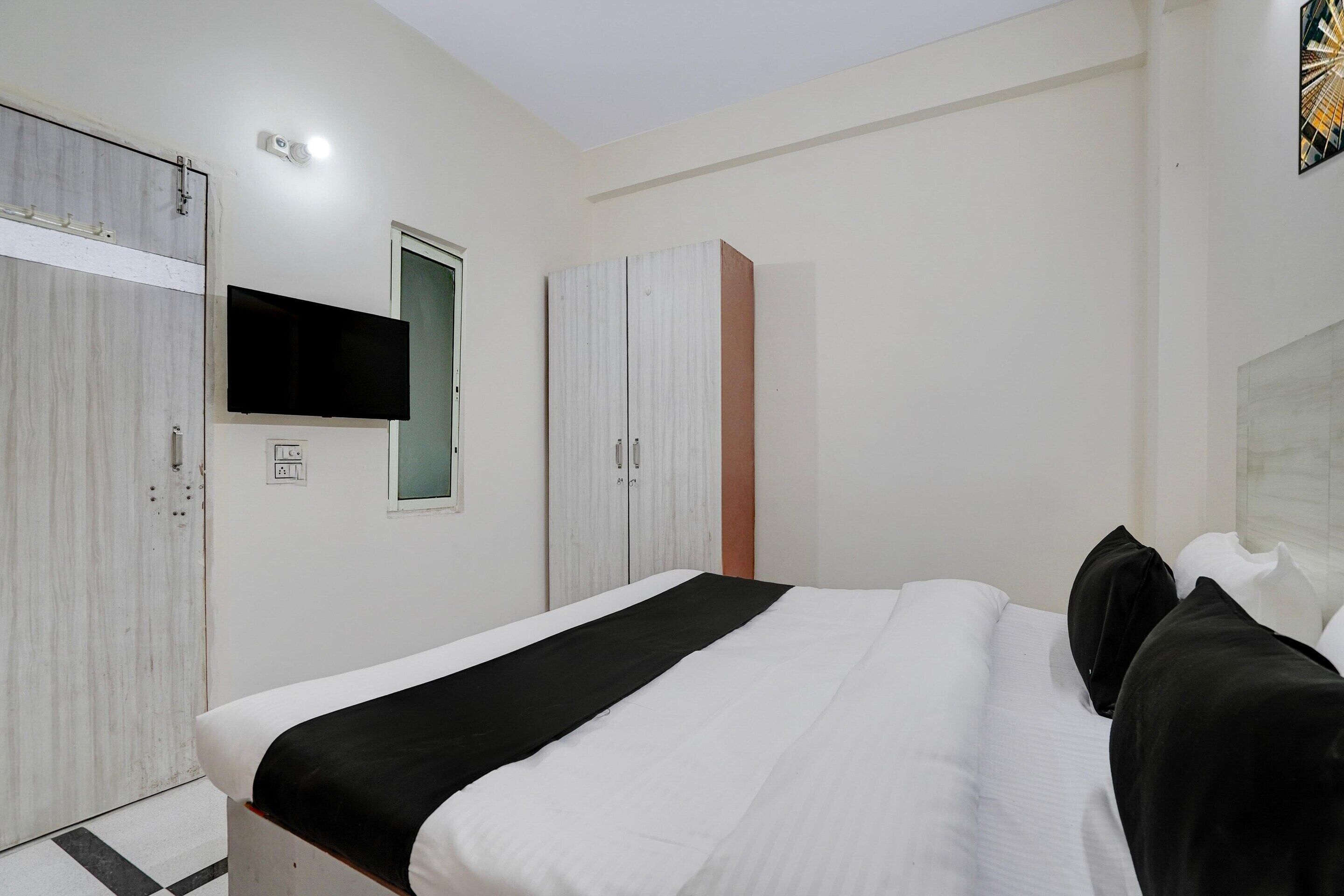 A bedroom with a bed, a wardrobe, a television, and a door.