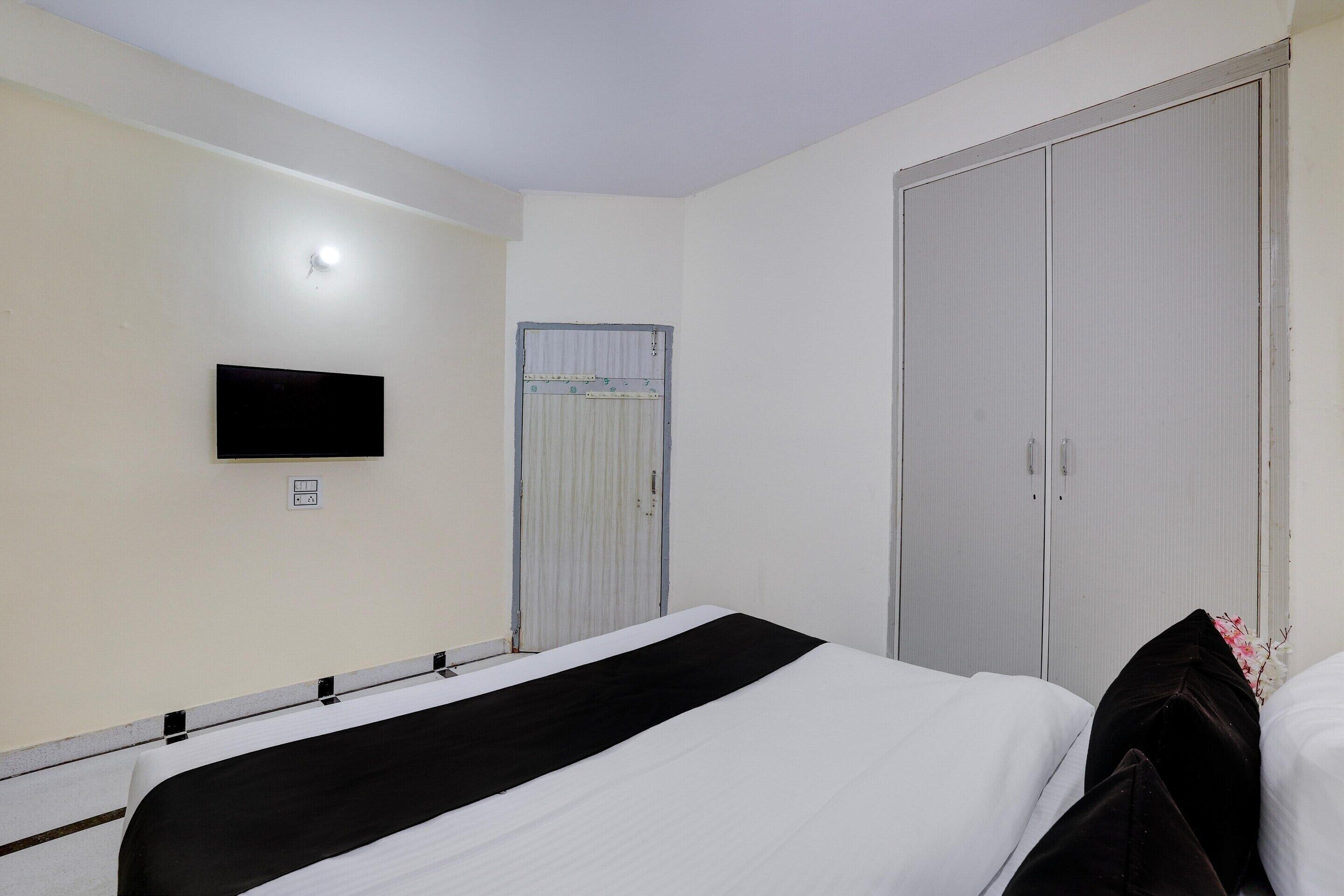 Una habitación de hotel con cama, televisor en la pared y armario.