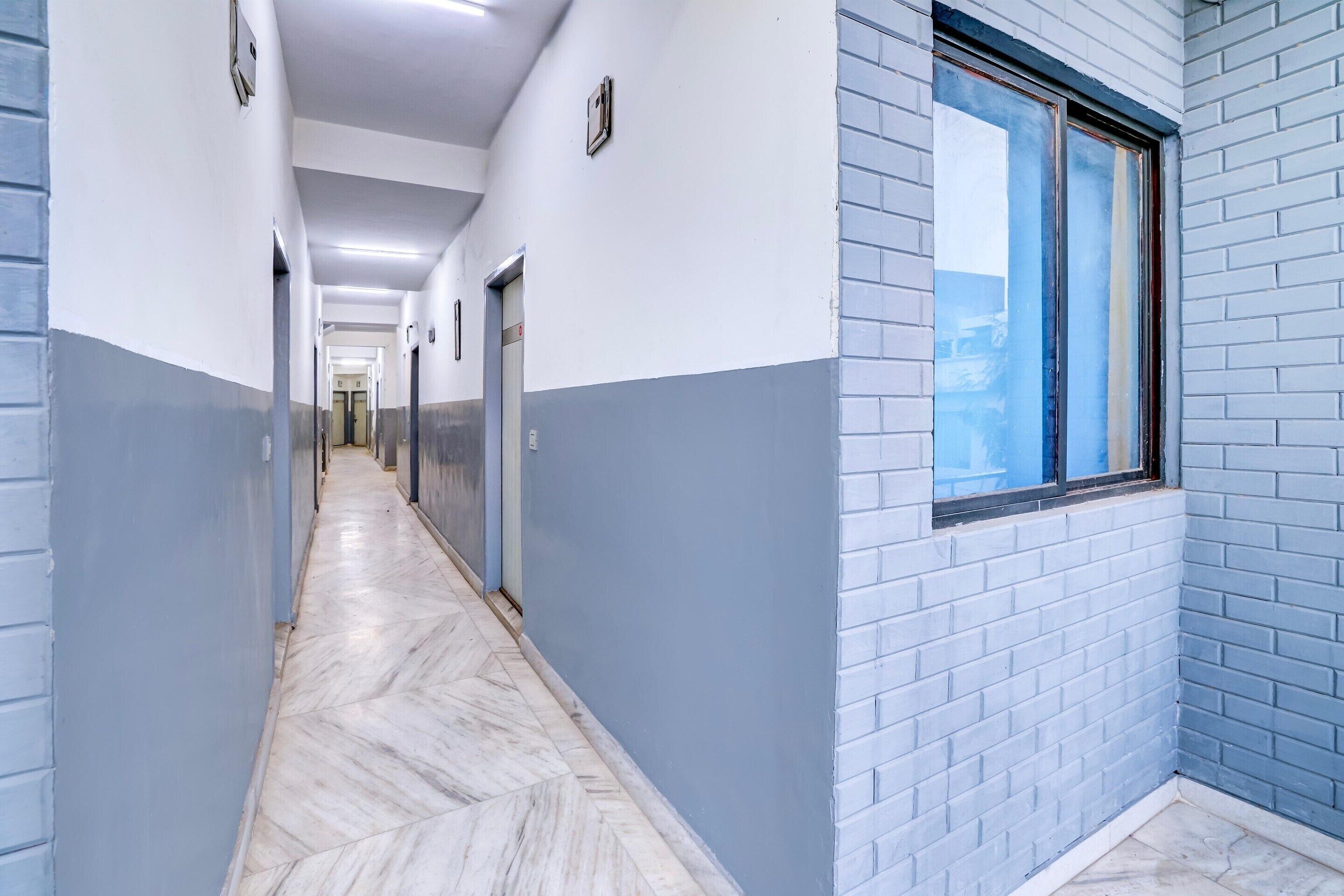A corridor with a herringbone floor, walls painted in two-tone blue and white, and a window with a view.