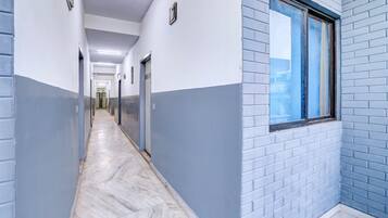 A corridor with a herringbone floor, walls painted in two-tone blue and white, and a window with a view.