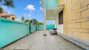 A narrow pathway leading to a building with a tiled floor and a manhole cover. - Deluxecrystal inn (Coimbatore)