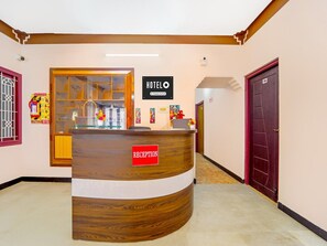 Un comptoir d’accueil d’hôtel avec une pancarte indiquant « réception », une pancarte indiquant les services de l’établissement et un espace d’accueil.