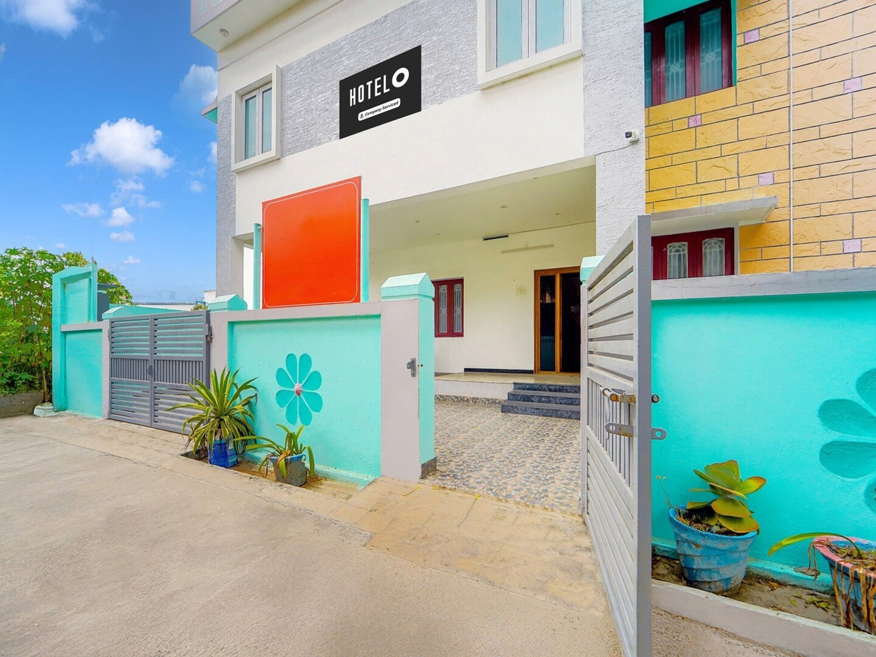 A hotel with a signboard, a gated entrance, and a staircase leading to the entrance.