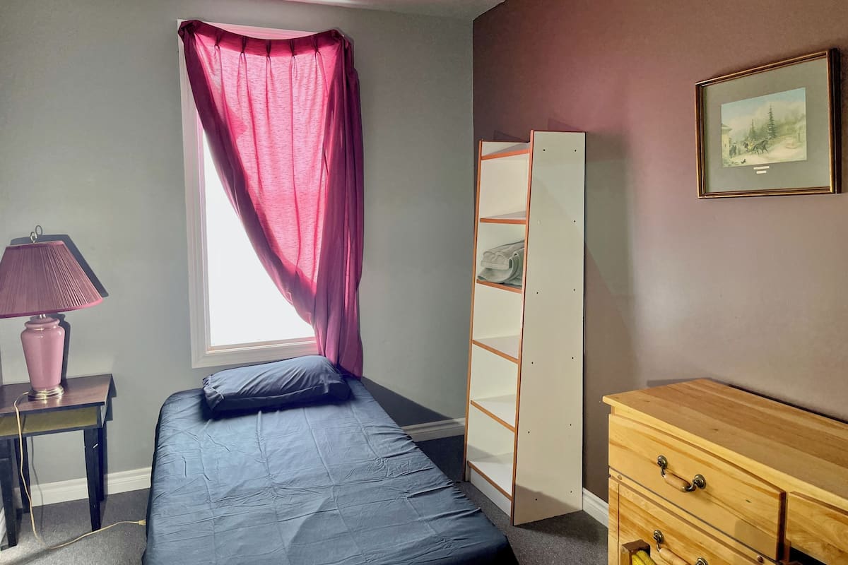 Une chambre à coucher comprenant un lit, une table de chevet avec une lampe, une armoire et une commode.