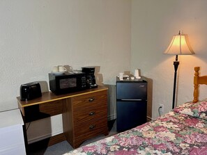 A compact room with a wooden desk, a black refrigerator, a microwave, a toaster, and a lamp. - Bennett Lodge (Daniel's Harbour)