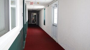 A hallway with a red carpet, white walls, and green trim. - Bennett Lodge (Daniel's Harbour)