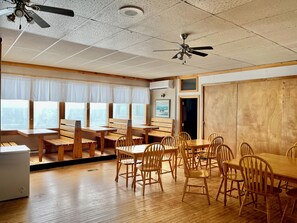 A restaurant with wooden furniture, a ceiling fan, and a view of the city. - Bennett Lodge (Daniel's Harbour)