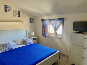 A bedroom with a bed, bedside table, lamp, TV, and curtains. - Casa Mare Holiday, Beachfront villa equipped with amenities and beach nearby (Sicilia)