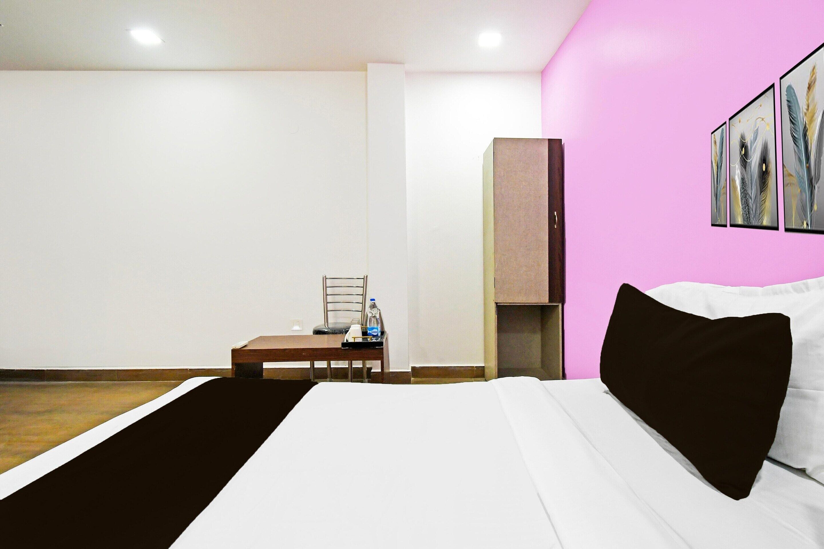 Hotellihuone, jossa on sänky, työpöytä, tuoli, vesipullo ja kaappi.