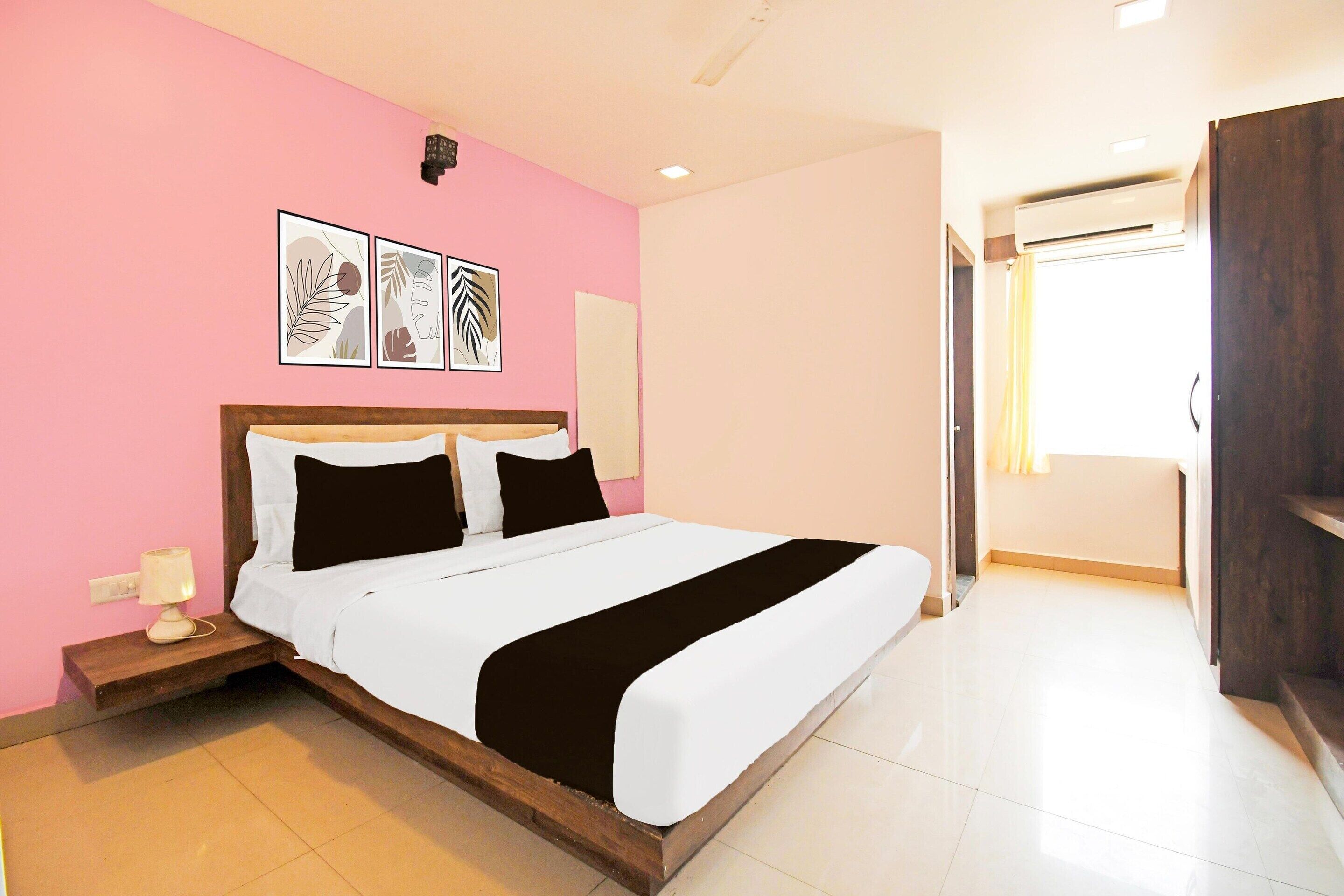 A hotel room with a bed, a nightstand, a wall-mounted air conditioner, and a door leading to another room.