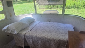 Un petit espace clos aménagé pour dormir, comprenant un lit, un oreiller et un banc.