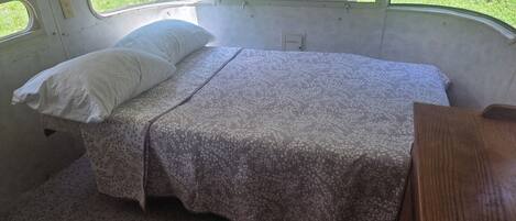 A small, enclosed sleeping area with a bed, a pillow, and a bench.