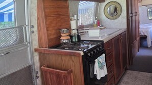 Une cuisine de taille réduite, avec des meubles de rangement en bois, une cuisinière et un évier.